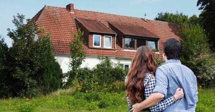 Two people in front of a house